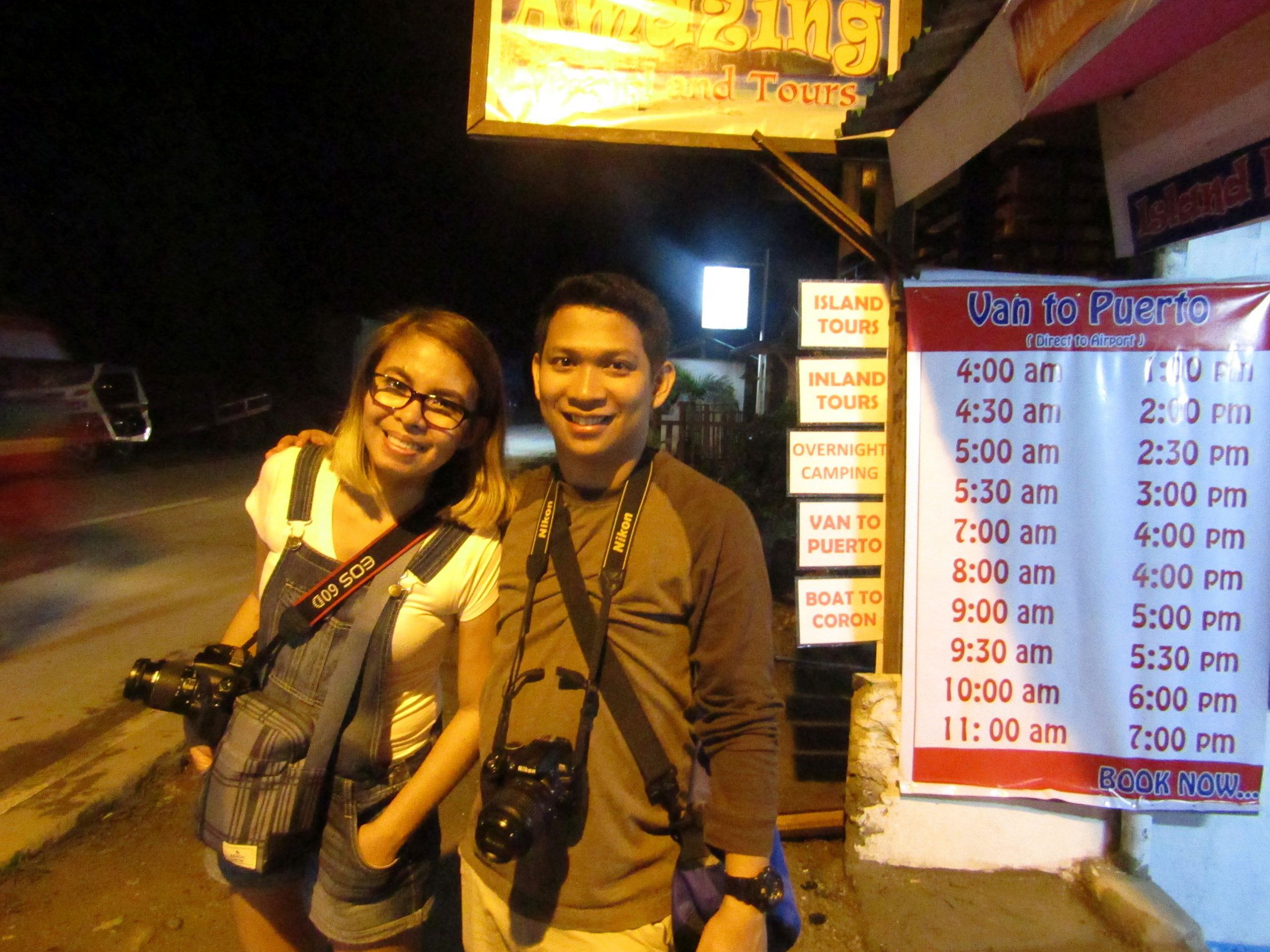 A roadside travel stall displays private van trip departure schedule from El Nido to Puerto Princesa..